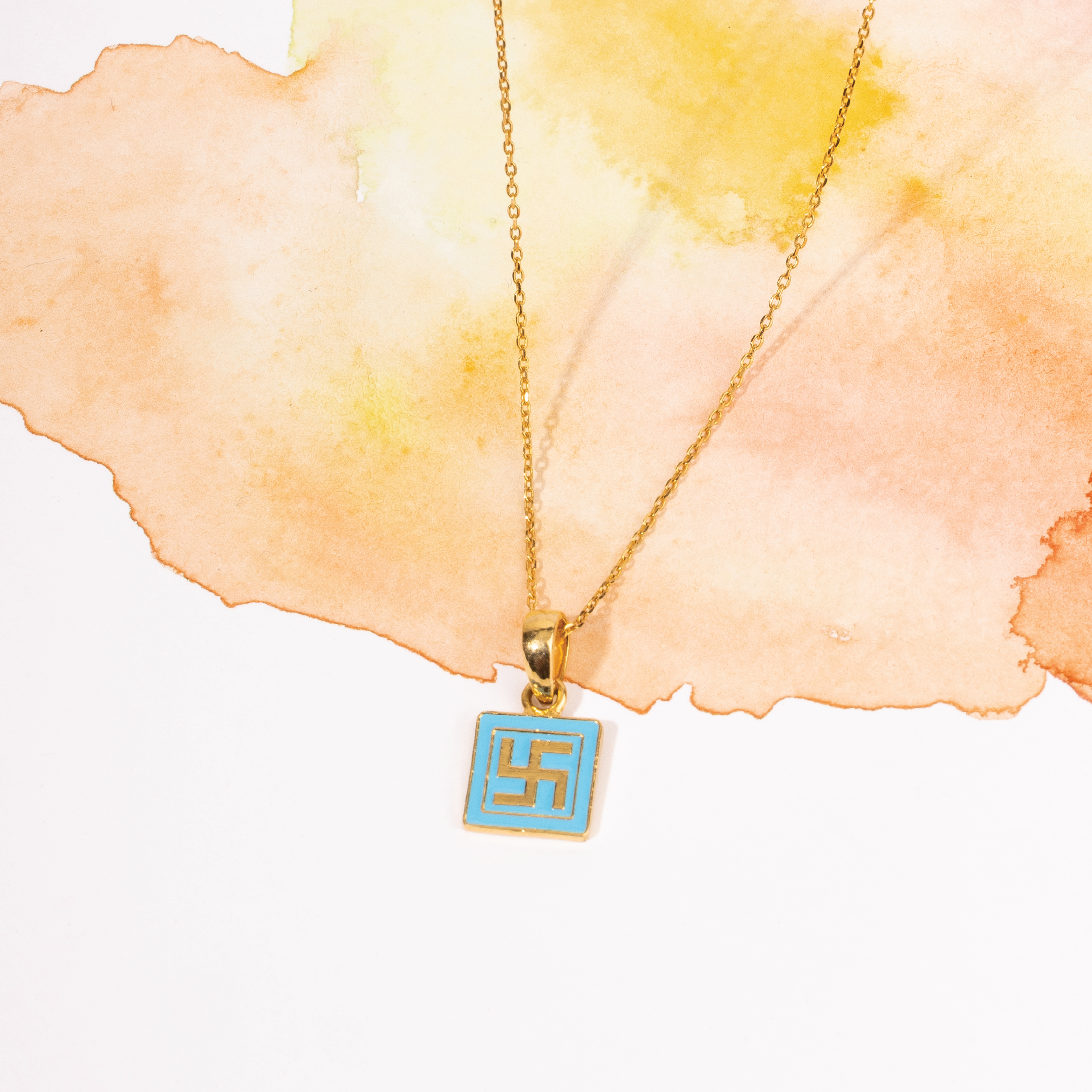 Tiny Jewels necklace with a blue pendant featuring a white symbol on a watercolor background