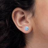 Tiny Jewels close-up of an ear wearing a blue earring with a clear gemstone.
