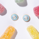 Tiny Jewels pair of round earrings with blue and gold accents on a white background with colorful jelly beans.