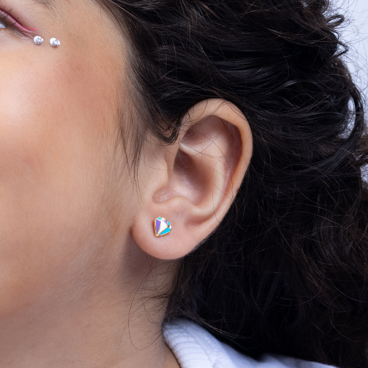 Tiny Jewels close-up of an ear with a colorful earring against a neutral background