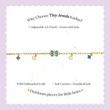 Tiny Jewels gold bracelet with blue accents on a wrist against a pink and black background