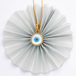 Tiny Jewels necklace with a circular pendant featuring an eye design on a white background