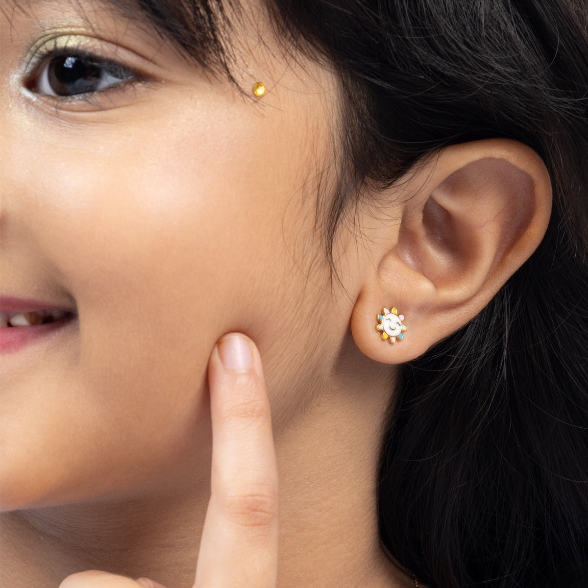 Tiny Jewels close-up of a person wearing a gold earring with a small flower design.