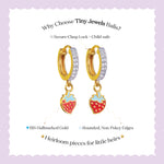 Tiny Jewels gold hoop earrings with strawberry charms on a white background with text about Tiny Jewels Balis.