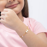 Tiny Jewels child wearing a gold bracelet with heart charms on a white background