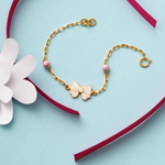 Tiny Jewels gold bracelet with a bow charm on a heart-shaped box with a white flower