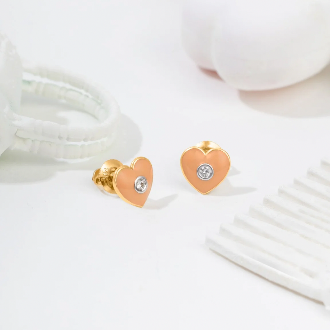 Tiny Jewels heart-shaped gold earrings with a central gemstone on a white background