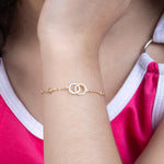 Tiny Jewels gold bracelet on a person's wrist with a pink and white top