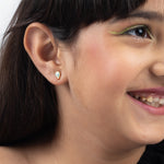Tiny Jewels close-up of a person wearing a gold earring with a green gemstone.
