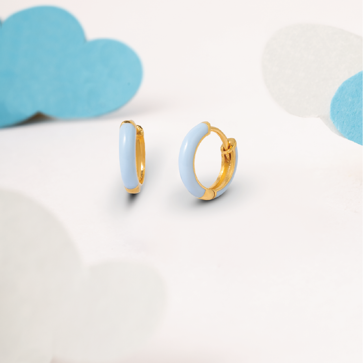 Tiny Jewels gold hoop earrings with light blue circular stones on a white background