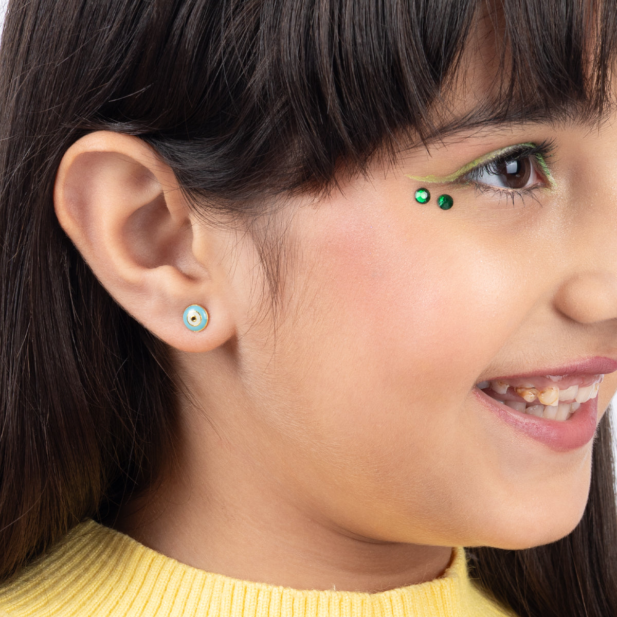 Tiny Jewels close-up of a girl wearing colorful earrings with a neutral background