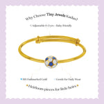 Tiny Jewels gold bracelet with a soccer ball charm on a light purple background, featuring text about Tiny Jewels Kadas.