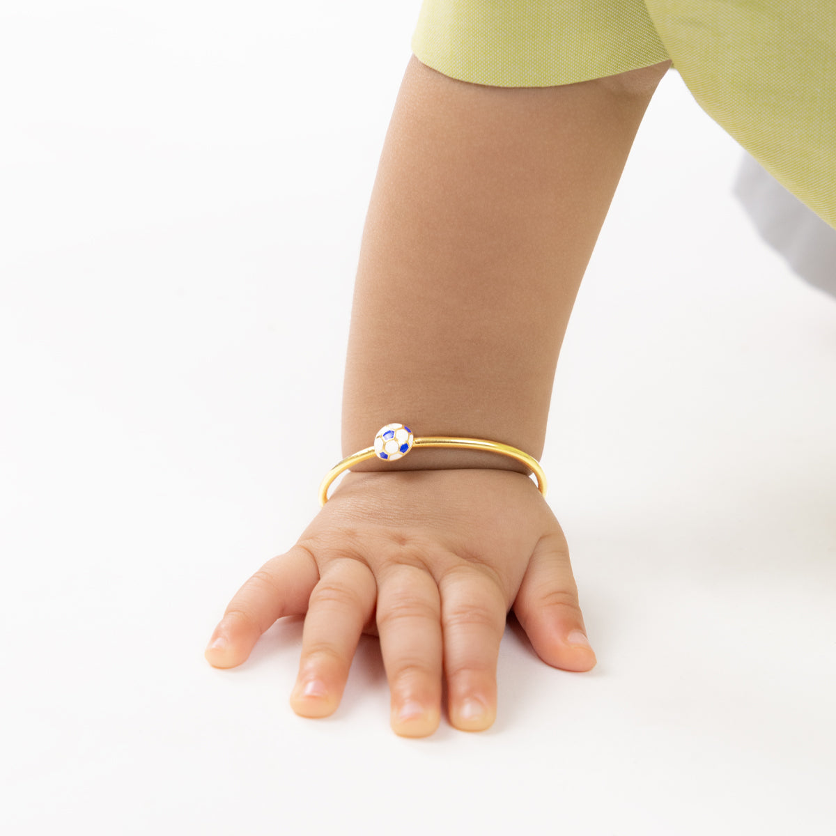 Tiny Jewels child's hand wearing a gold bracelet with a blue gemstone on a white background