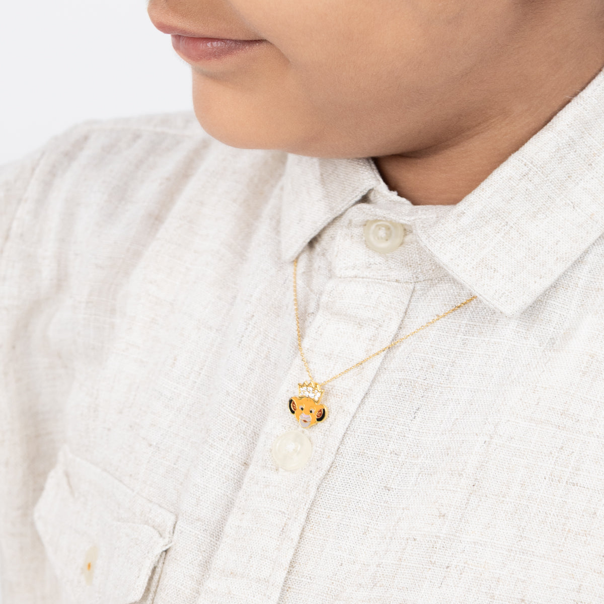 Tiny Jewels child wearing a gold necklace with a small pendant on a white shirt