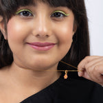 Tiny Jewels woman holding a gold necklace with a pink pendant against a white background