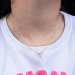 Tiny Jewels necklace with small pink beads worn by a person on a white background