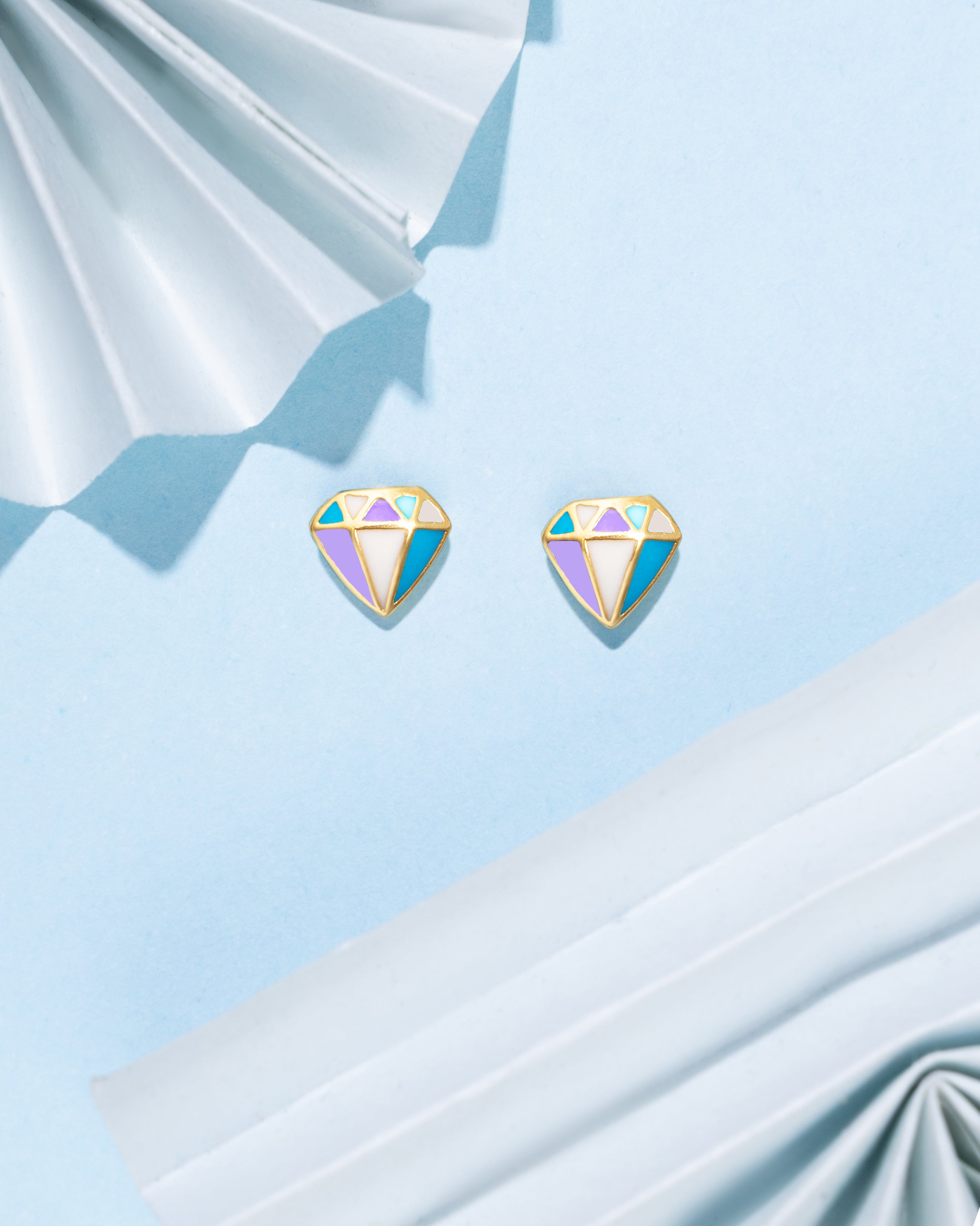 Tiny Jewels colorful gemstone earrings on a light blue fabric background