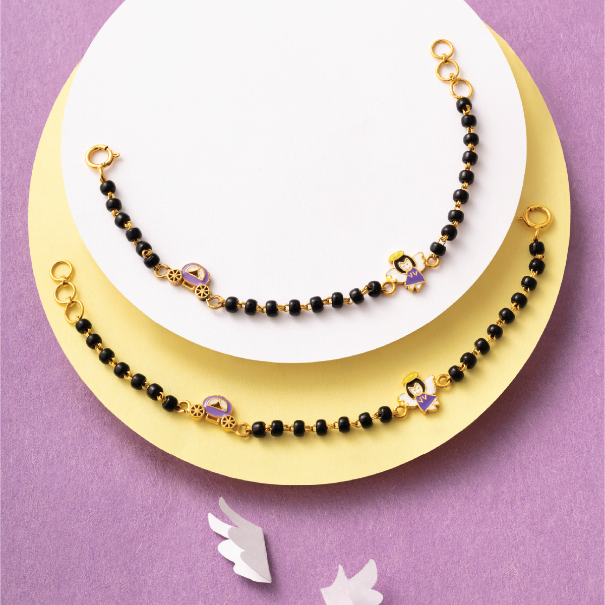 Tiny Jewels black beaded necklace with gold accents on a white plate against a purple background