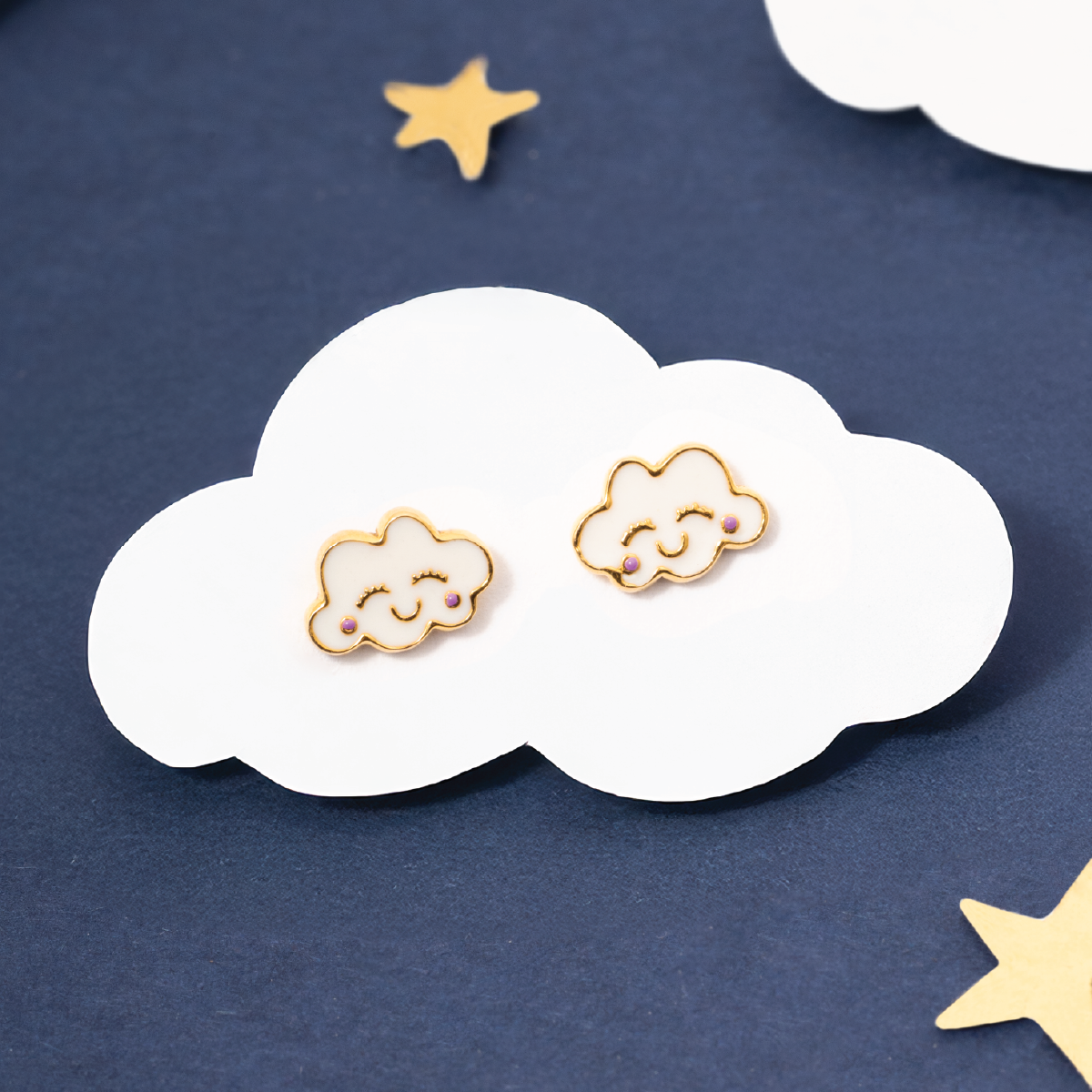 Tiny Jewels cloud-shaped earrings on a cloud with stars in the background