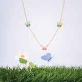 Tiny Jewels necklace with butterfly pendants on a grassy background