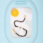 Tiny Jewels black and gold beaded bracelet on a white stand with a blue background