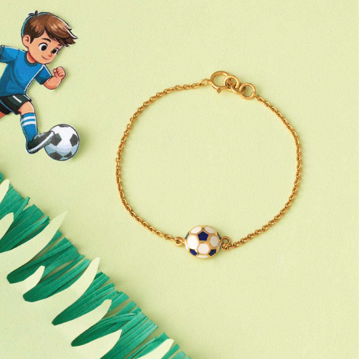 Tiny Jewels gold bracelet with a soccer ball charm on a light green background with a soccer-themed illustration.