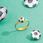 Tiny Jewels gold ring with a soccer ball charm on a green background with soccer ball decorations.