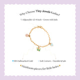 Tiny Jewels gold bracelet with charms on a light purple background, featuring text about Tiny Jewels Kadas.