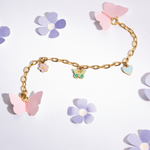 Tiny Jewels gold bracelet with butterfly and flower charms on a light background