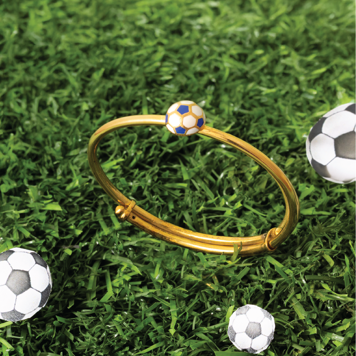Tiny Jewels gold bracelet with a soccer ball charm on grass