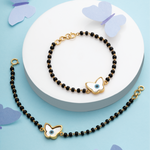 Tiny Jewels black beaded bracelet with gold butterfly charms on a white plate against a blue background