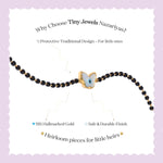 Tiny Jewels black beaded bracelet with a gold butterfly charm on a light purple background, featuring text about Tiny Jewels Nazariyas.