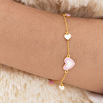 Tiny Jewels gold bracelet with heart-shaped charms on a wrist against a soft background