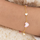 Tiny Jewels gold bracelet with heart-shaped charms on a wrist against a soft background