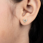 Tiny Jewels close-up of an ear wearing a small blue and gold earring.