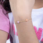 Tiny Jewels gold anklet with pink heart charms on a person's ankle, wearing a white and pink outfit.