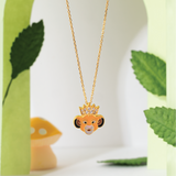 Tiny Jewels gold necklace with a lion-shaped pendant on a white background with green leaves.