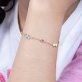 Tiny Jewels gold bracelet with colorful stones on a wrist against a white background