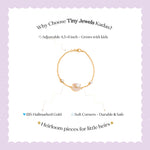 Tiny Jewels gold bracelet with a heart design on a light purple background, featuring text about Tiny Jewels Kadas.
