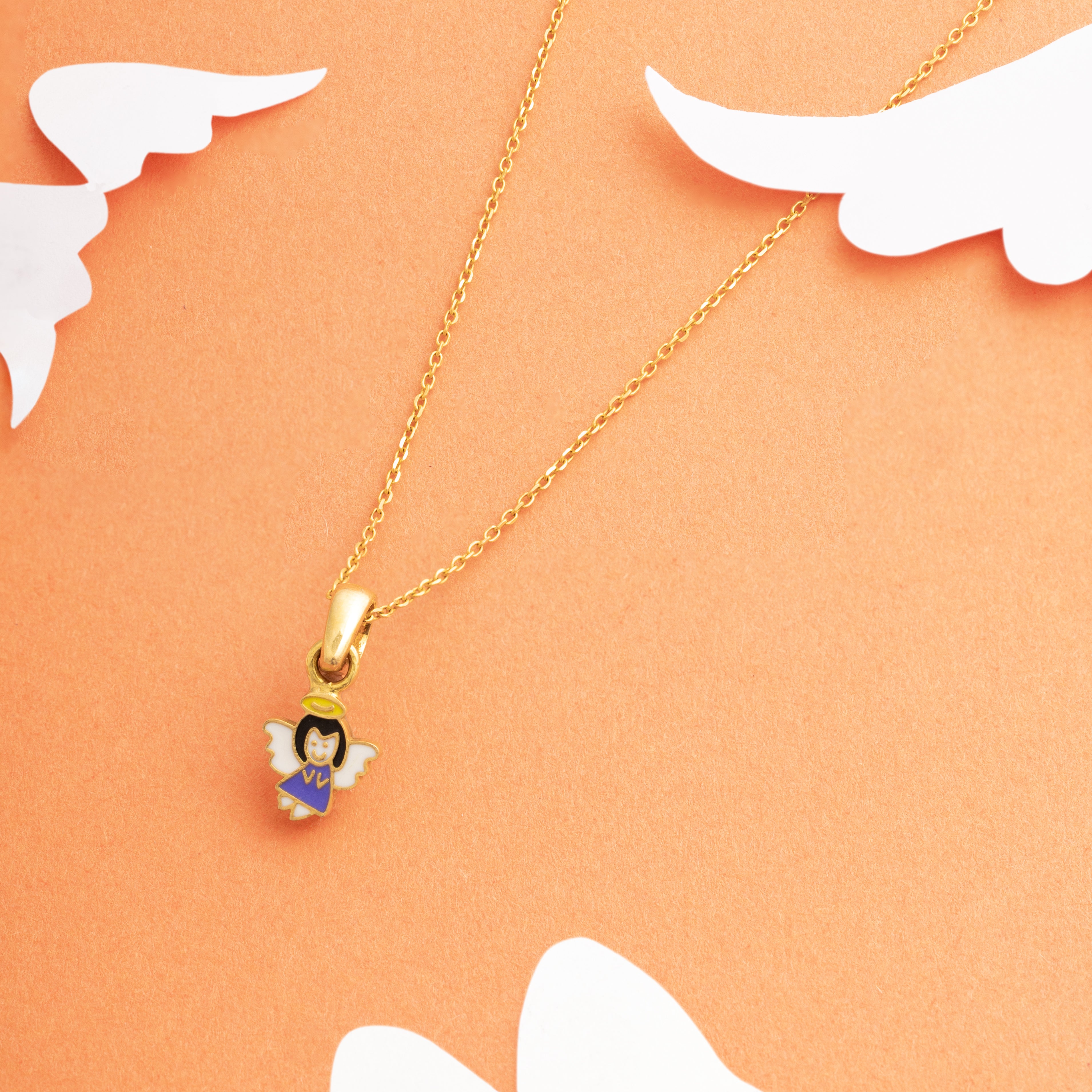 Tiny Jewels gold necklace with an angel pendant on a peach background