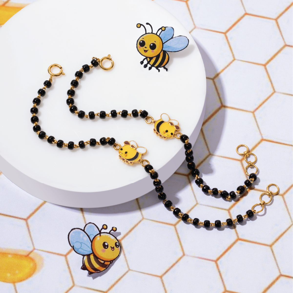 Tiny Jewels black beaded necklace with bee charms on a white plate with a honeycomb pattern