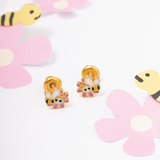 Tiny Jewels gold bee and flower earrings on a white background with pink flowers.