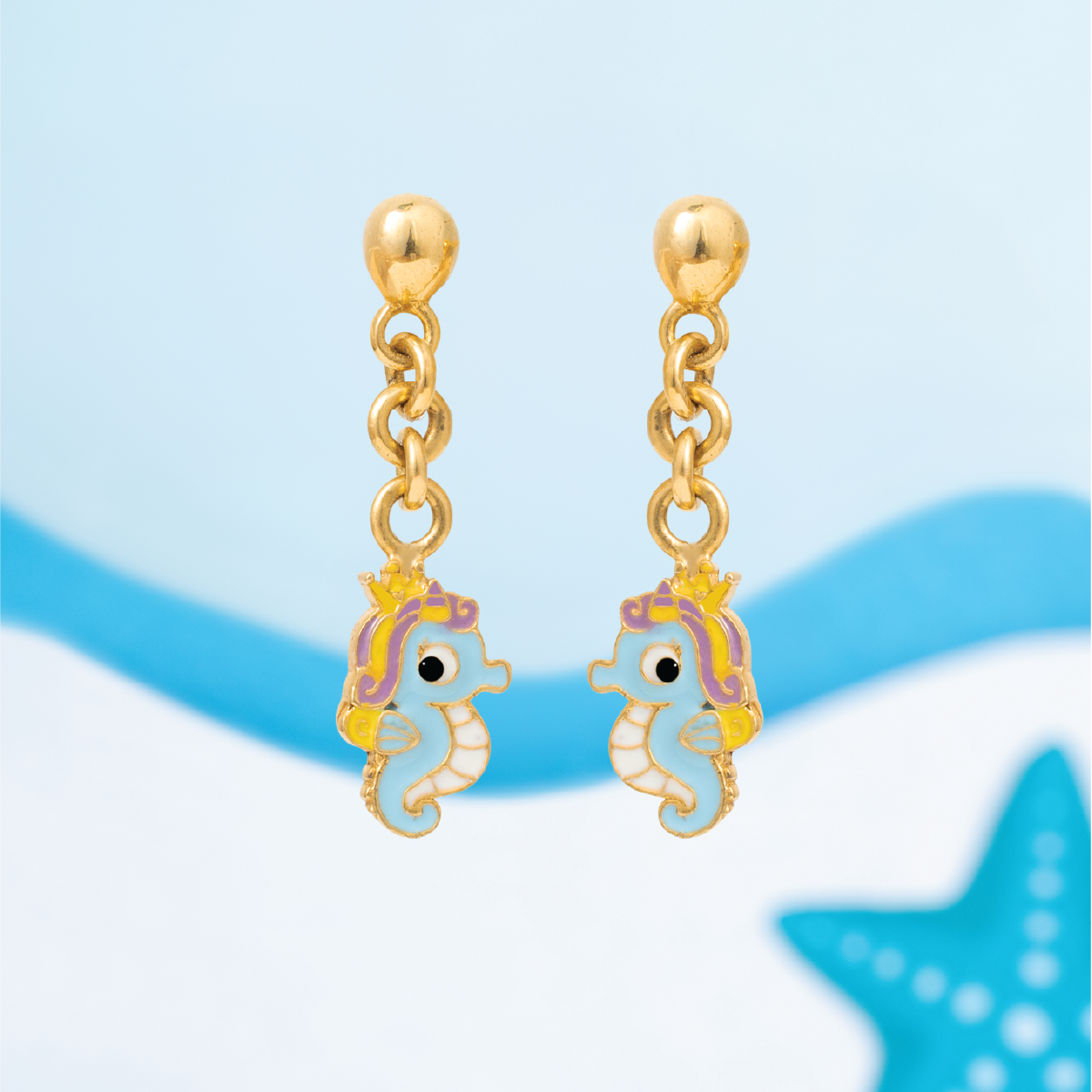 Tiny Jewels gold earrings with seahorse designs on a blue background