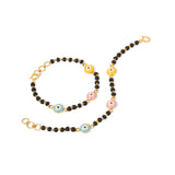 Tiny Jewels necklace with black beads, gold chain, and colorful evil eye charms on a white background