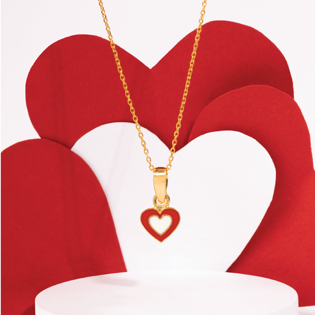 Tiny Jewels Gold necklace with a heart-shaped pendant on a red heart-shaped background
