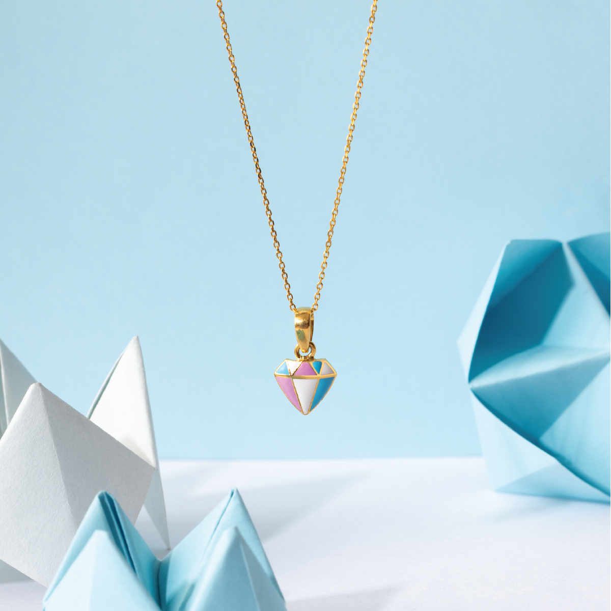 Tiny Jewels necklace with a colorful geometric pendant against a light blue background with origami elements.