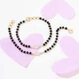 Tiny Jewels black beaded necklace with gold accents on a white background